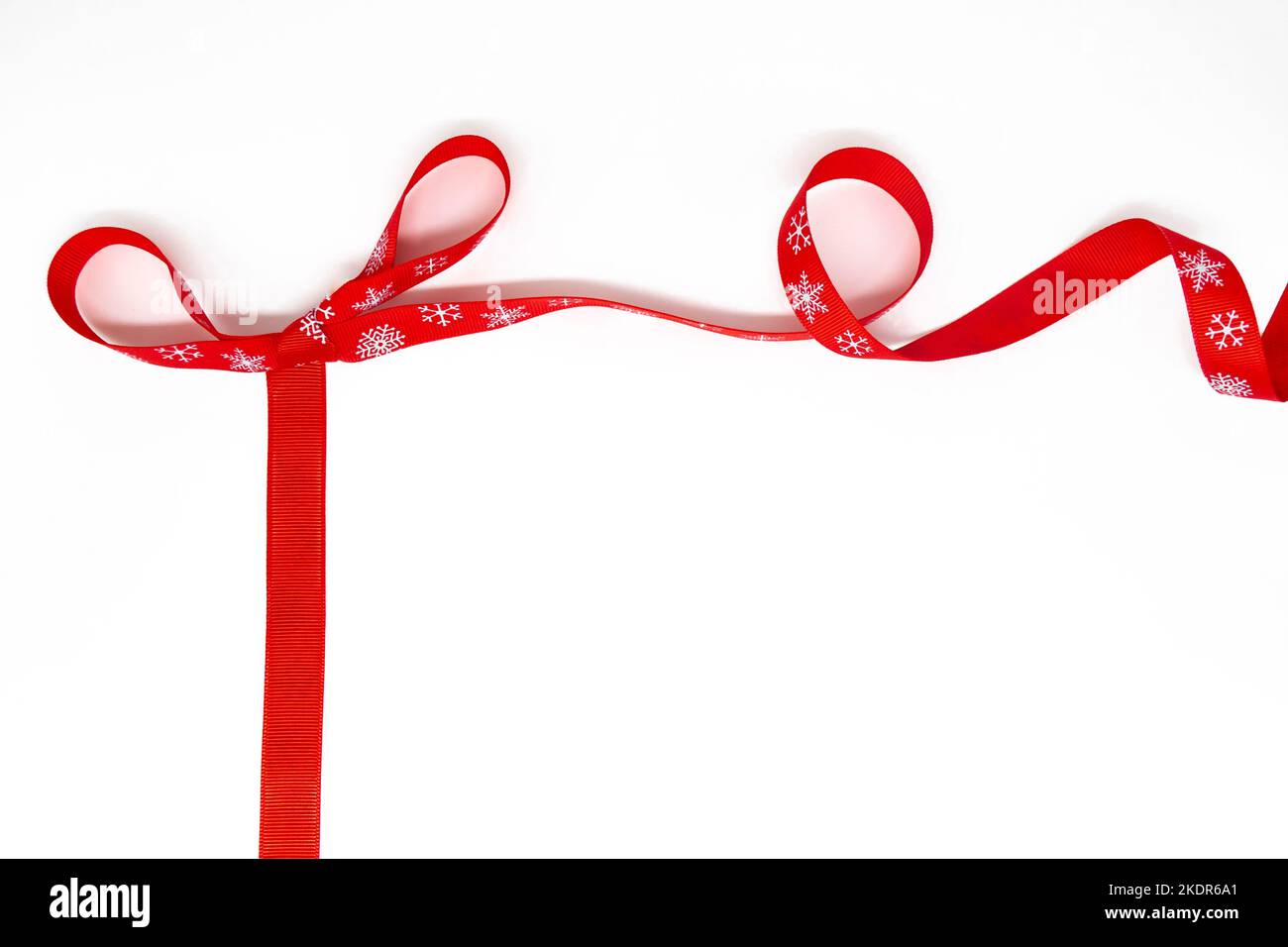 Un arco di rosso arricciante nastro luminoso con fiocchi di neve come cornice. Sfondo bianco, spazio di copia. Il concetto di Natale, San Valentino, regali. Foto Stock