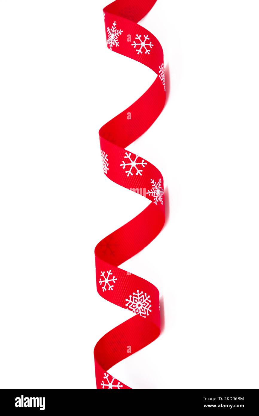 Un nastro rosso riccio luminoso con fiocchi di neve su sfondo bianco. Spazio di copia. Immagine verticale. Il concetto di Natale, San Valentino e regali. Foto Stock
