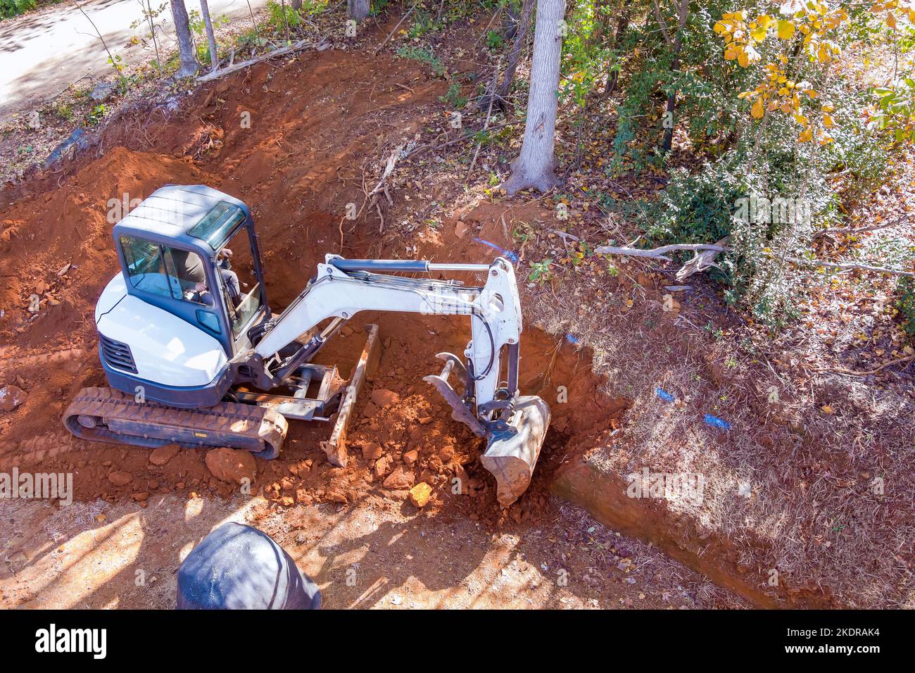Terreno di scavo della benna del trattore durante i lavori di movimento terra in cantiere utilizzando un escavatore cingolato Foto Stock