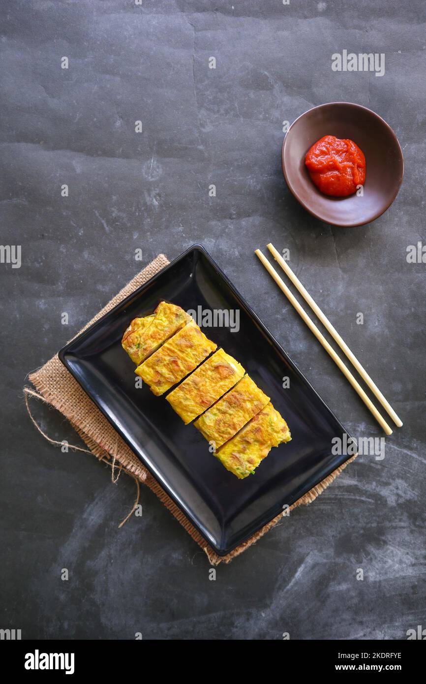 Telur dadar gulung o Tamagoyaki o Japaneses uovo rotolo. Gyeran Mari o Coreano arrotolato omelette. Uovo fritto Foto Stock