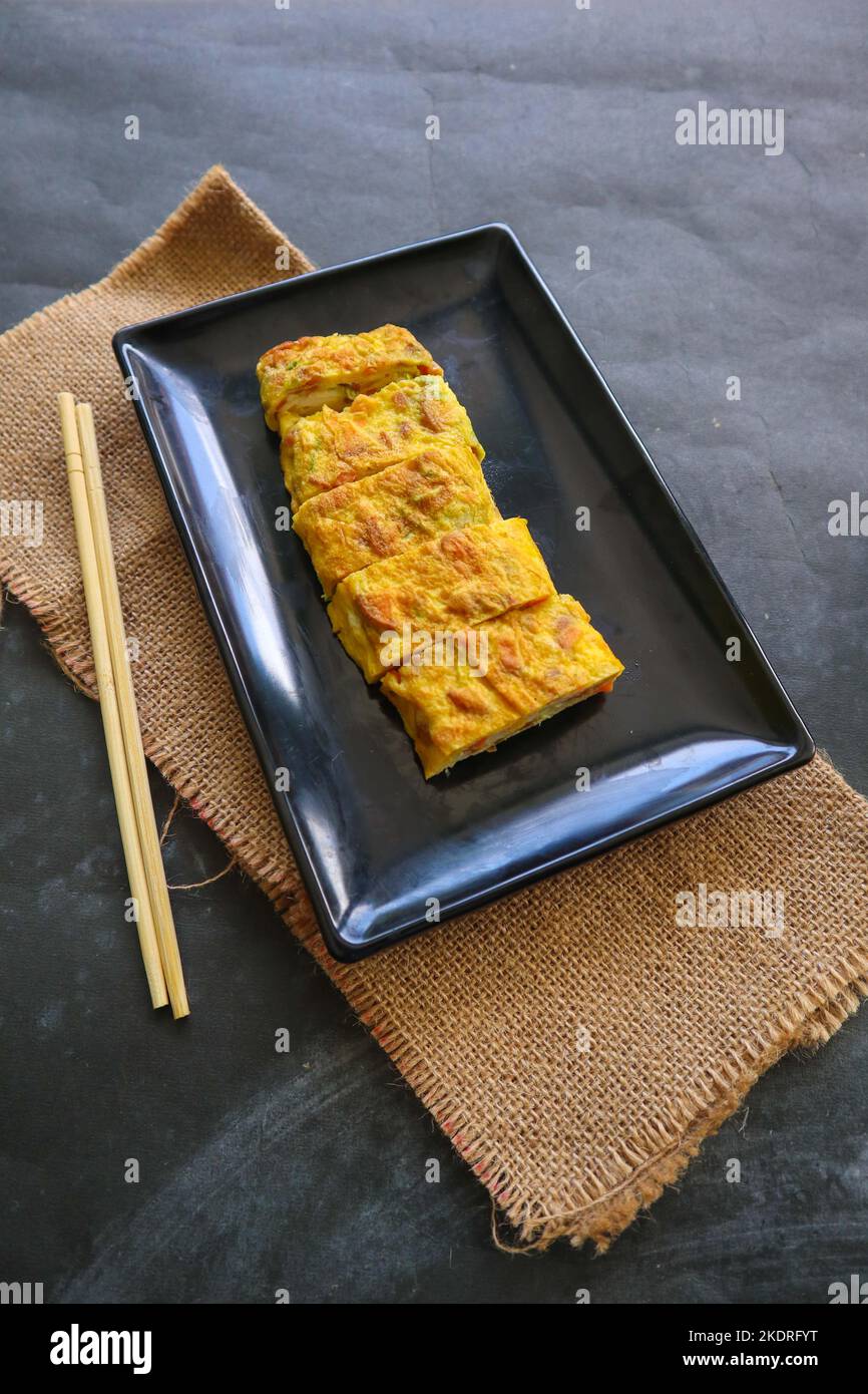 Telur dadar gulung o Tamagoyaki o Japaneses uovo rotolo. Gyeran Mari o Coreano arrotolato omelette. Uovo fritto Foto Stock