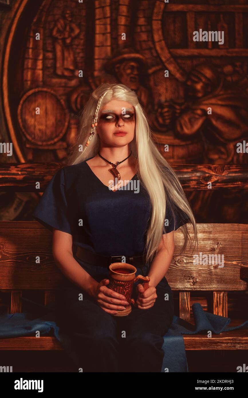 Donna vichinga con una tazza in abiti guerrieri tradizionali all'interno di un pub. Foto Stock