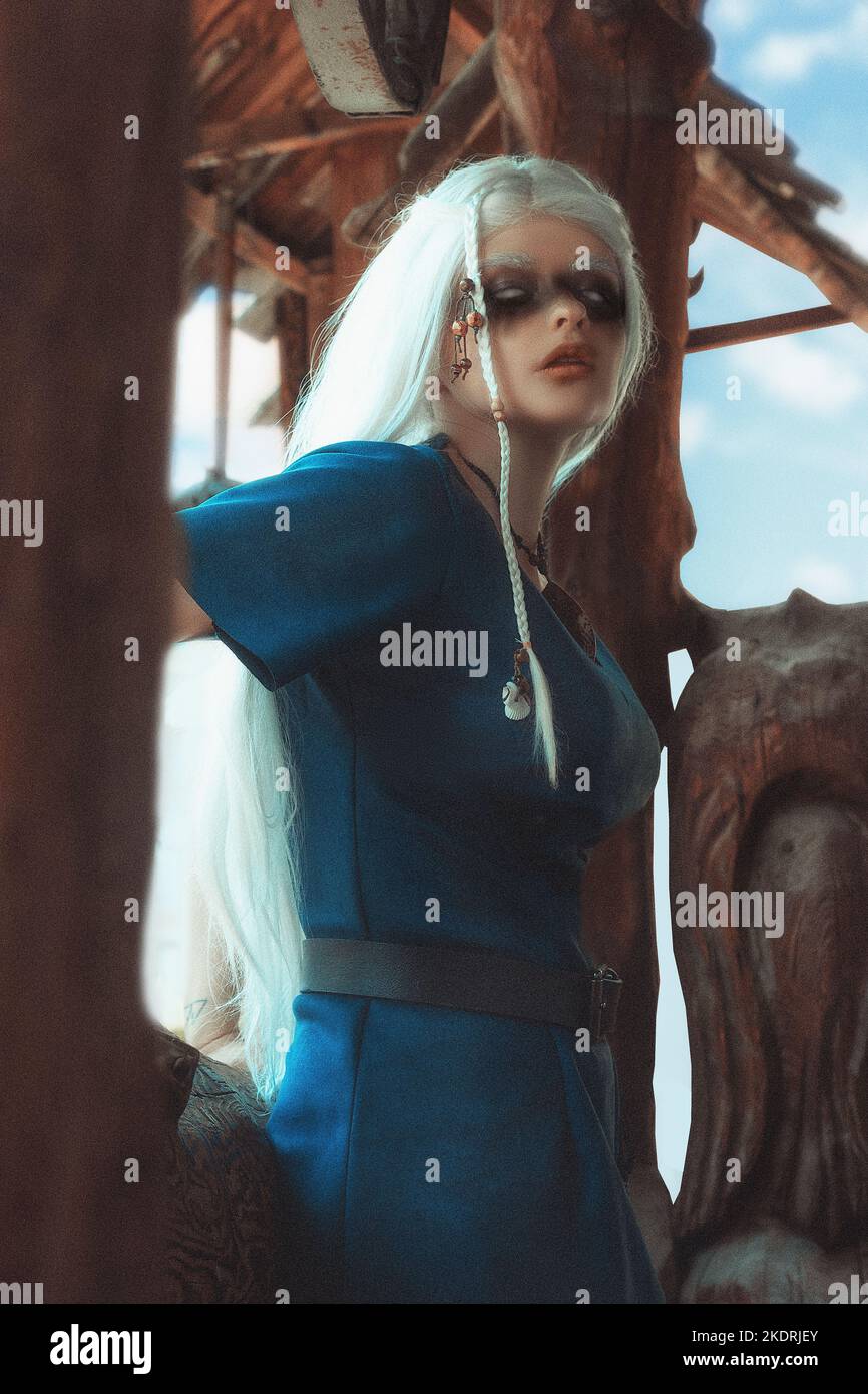 Donna vichinga in abiti da guerriero tradizionali. Sullo sfondo di una grande villa vichinga. Foto Stock