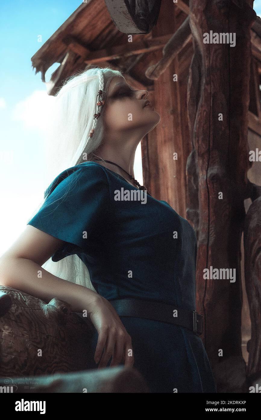 Donna vichinga in abiti da guerriero tradizionali. Sullo sfondo di una grande villa vichinga. Foto Stock