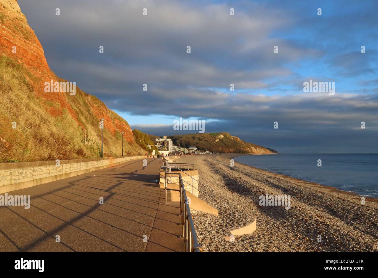 Un cielo tempestoso e il sole della sera sulla spianata a Seaton, in Devon sulla costa giurassica della baia di Lyme Foto Stock