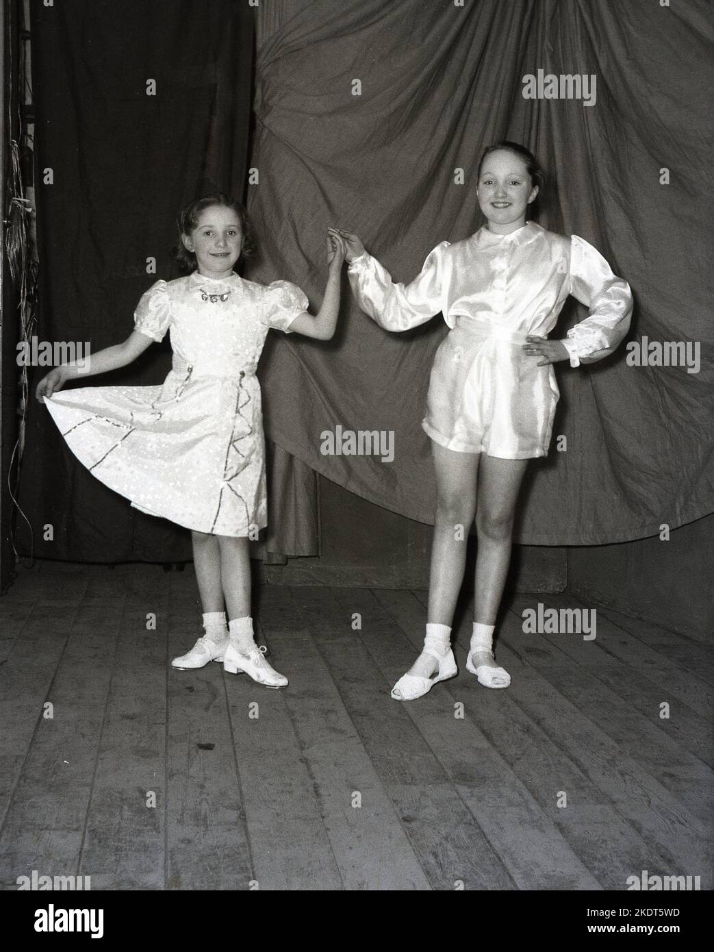 1955, storico, due giovani ragazze che appaiono nella pantomina invernale, Robin Hood, nei loro costumi, in posa insieme sul palco per una foto, Leeds, Inghilterra, Regno Unito. Foto Stock