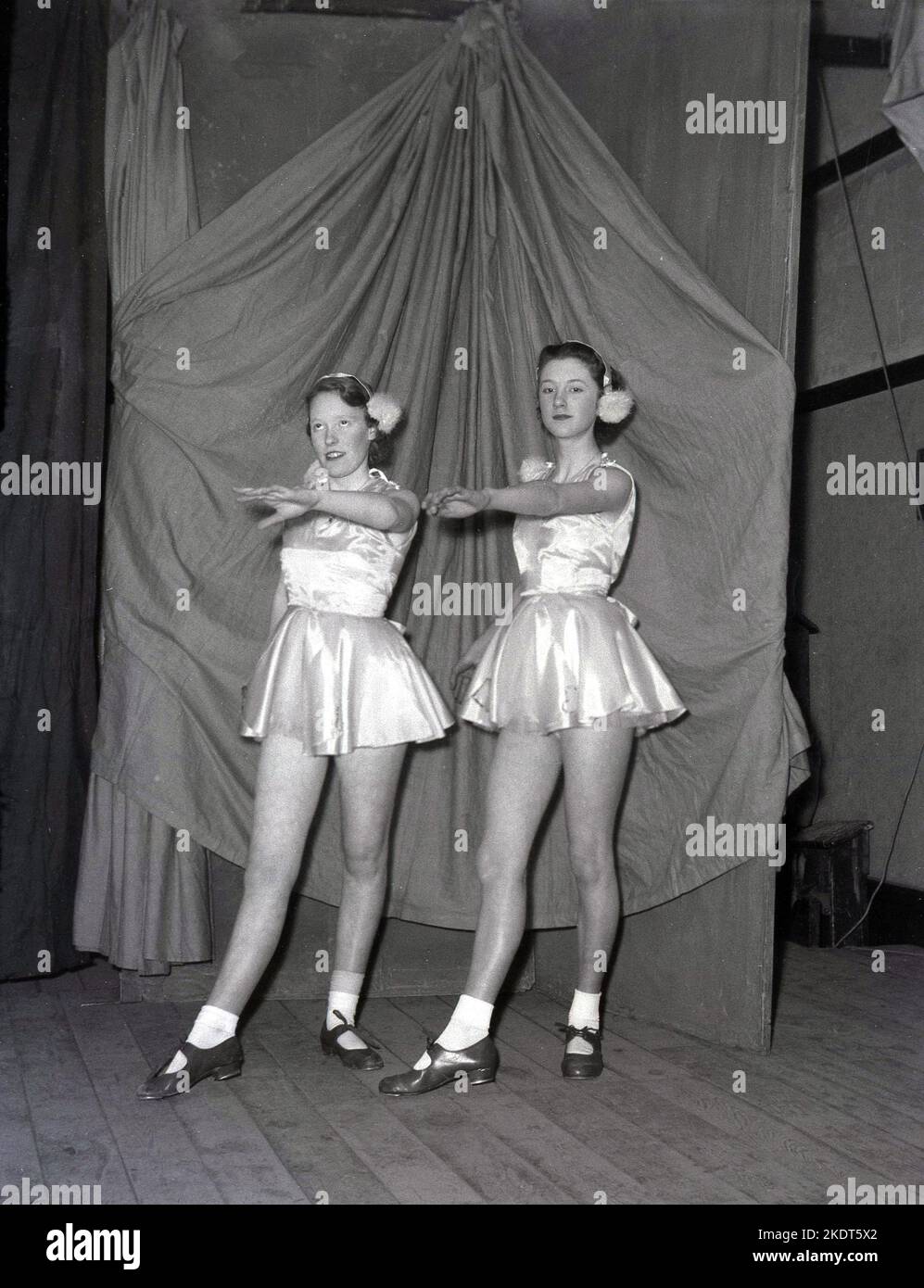 1955, storico, due ragazze adolescenti più grandi, ballerini, che appaiono nella pantomina d'inverno, Robin Hood, sul palco, nei loro abiti di abiti corti calze boblle e scarpe da ballo, in posa per una foto, Leeds, Inghilterra, UK. Foto Stock