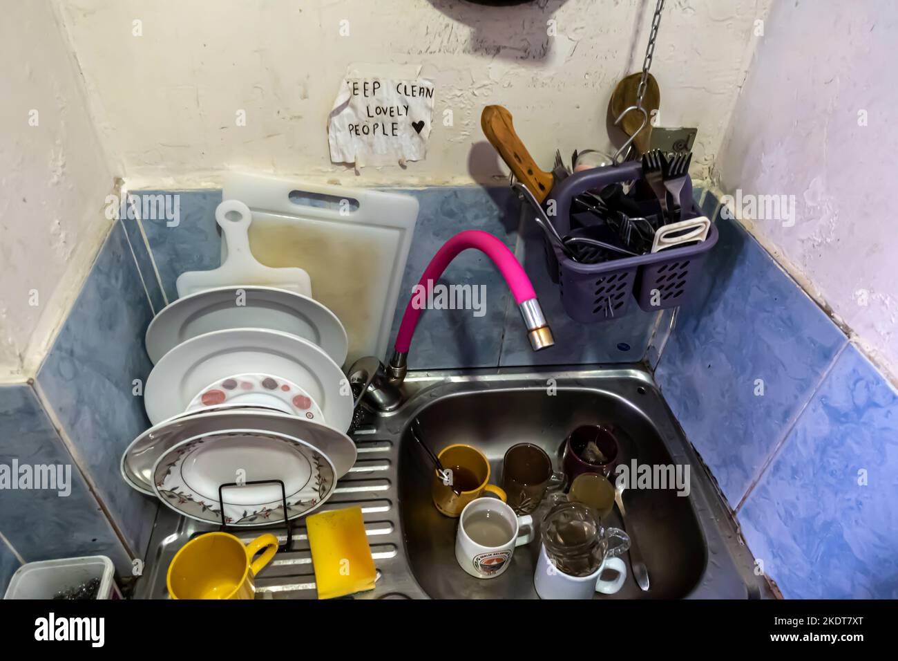 I piatti sporchi non lavati nel lavandino con un cartello "Keep Clean Lovely People". tema - cucina condivisa, spazio comune condiviso. Foto Stock