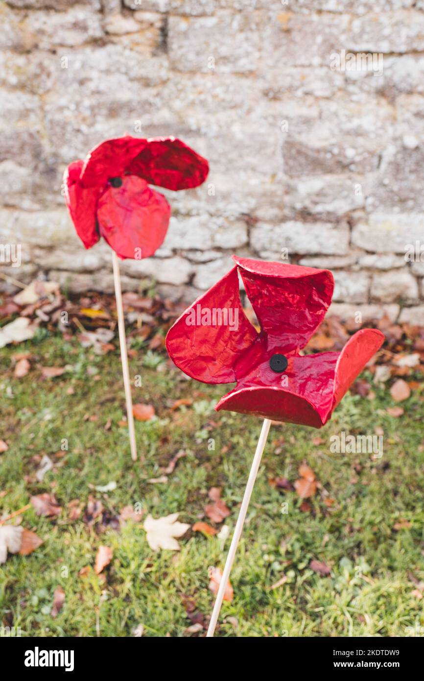 Papaveri di ceramica spinti nel terreno nel cimitero della Chiesa di Santa Maria, Witney per la Giornata della memoria Foto Stock