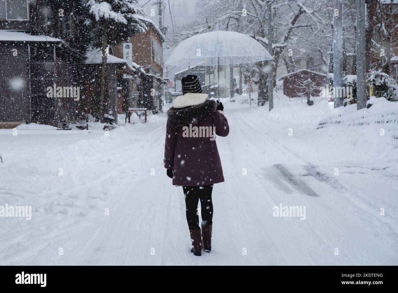 Viaggio in Giappone, ragazza con ombrello a piedi sul sentiero nel villaggio in inverno. Foto Stock