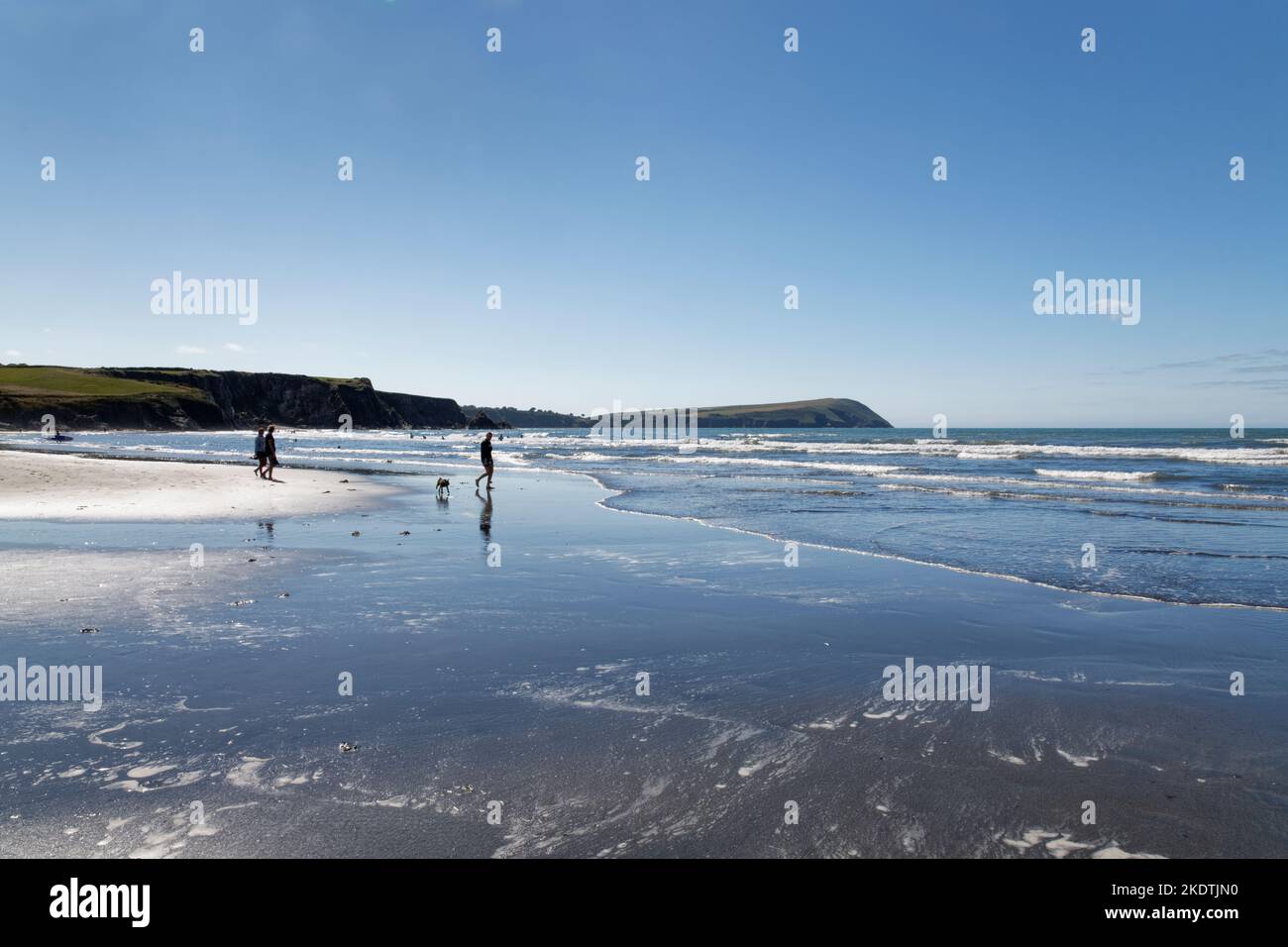 Persone che camminano sulla spiaggia di Newport Sands su una marea in arrivo, con Dinas Head sullo sfondo, Pembrokeshire, Galles, Regno Unito, luglio 2022. Foto Stock