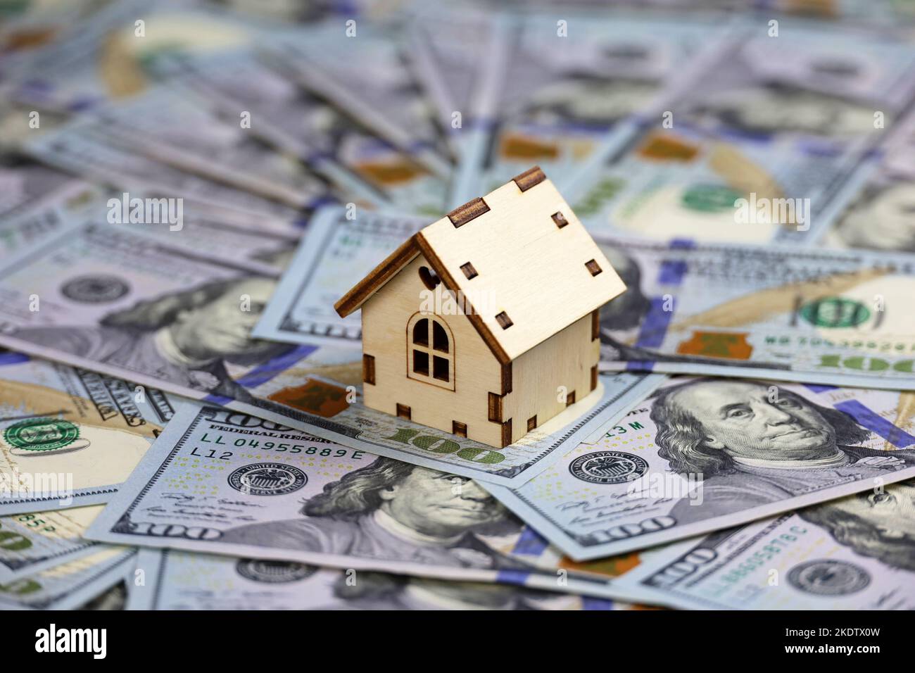 Modello di casa in legno sullo sfondo di banconote in dollari USA. Mercato immobiliare, acquisto o affitto di immobili Foto Stock