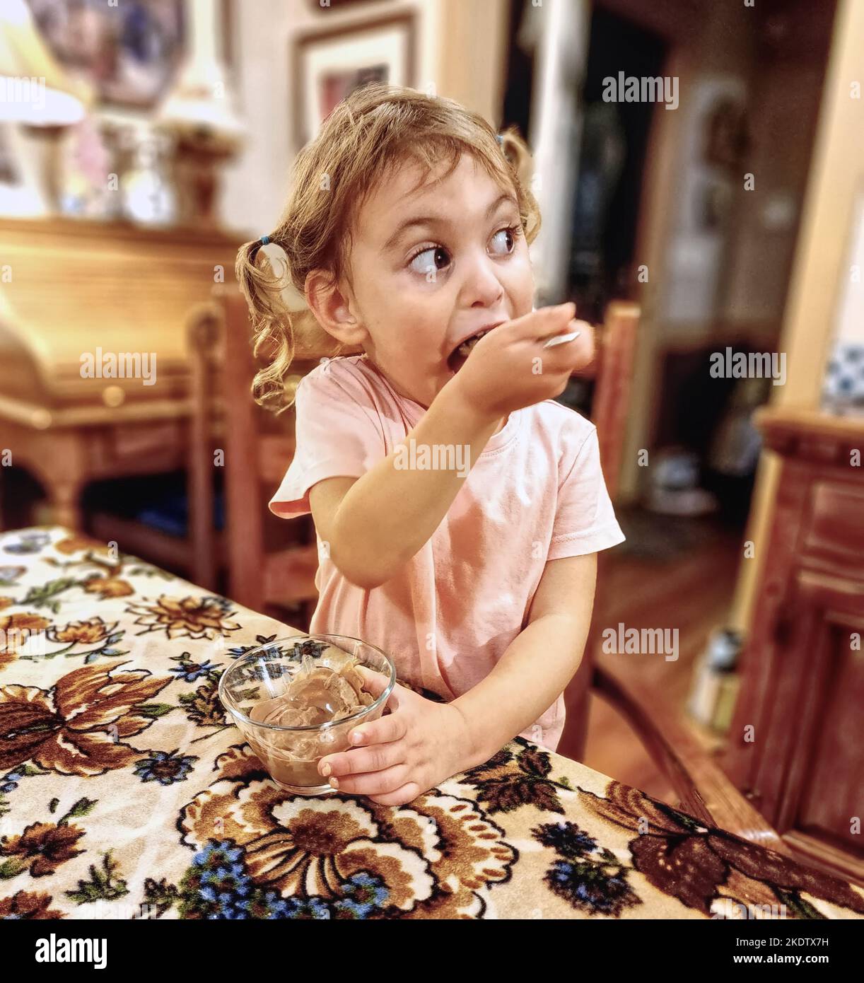 Bambina che mangia gelato e guarda qualcosa sulla sua sinistra Foto Stock