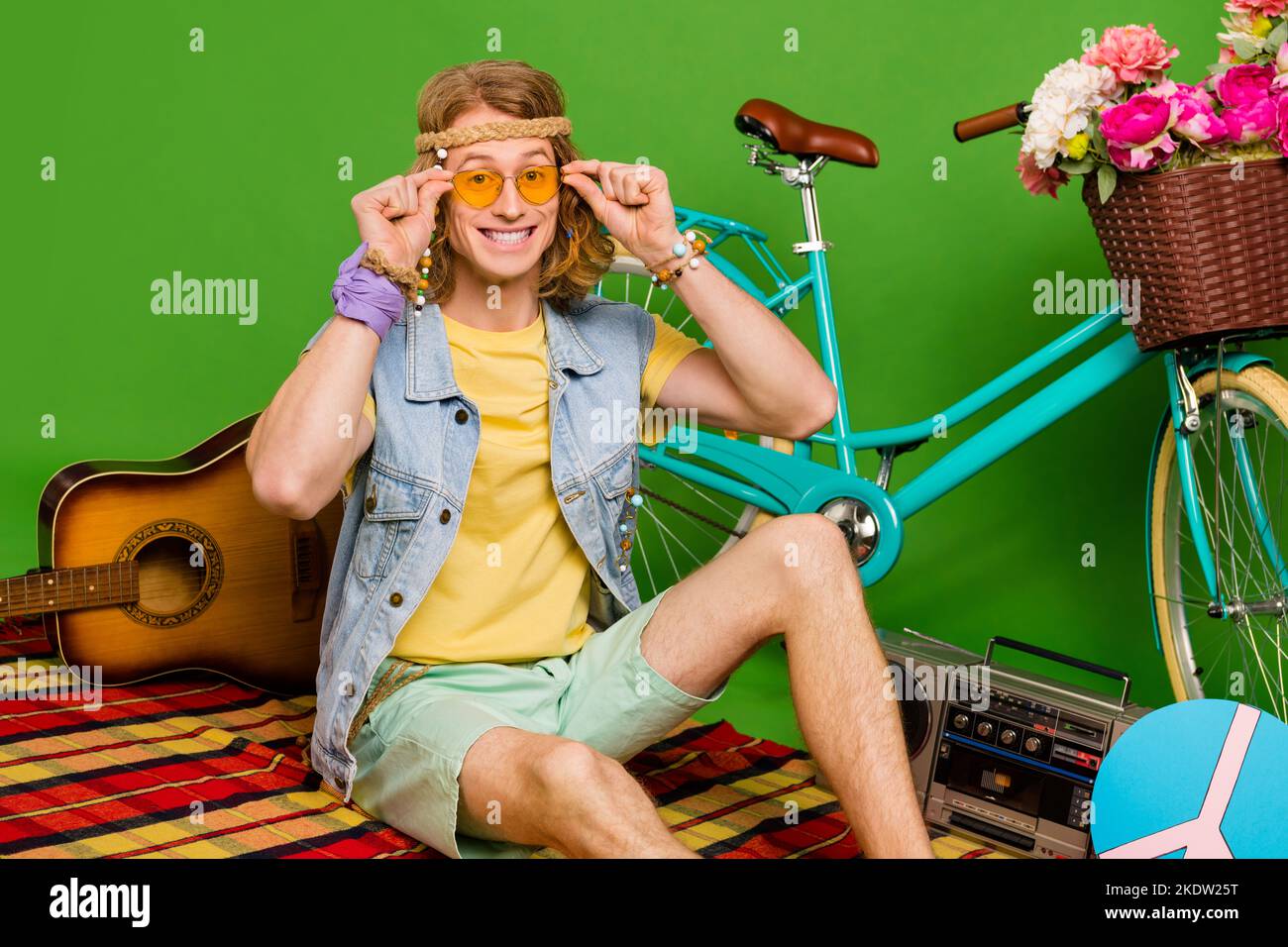 Foto di allegro persona toccare occhiali sedersi coperta plaid natura unità isolato su sfondo verde Foto Stock
