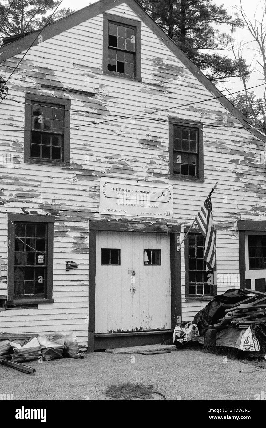 Un edificio in legno vintage indossato dalle intemperie con un cartello in tela che legge il Trusted Hammer LLC in Union, New Hampshire. L'immagine è stata acquisita in nero analogico Foto Stock