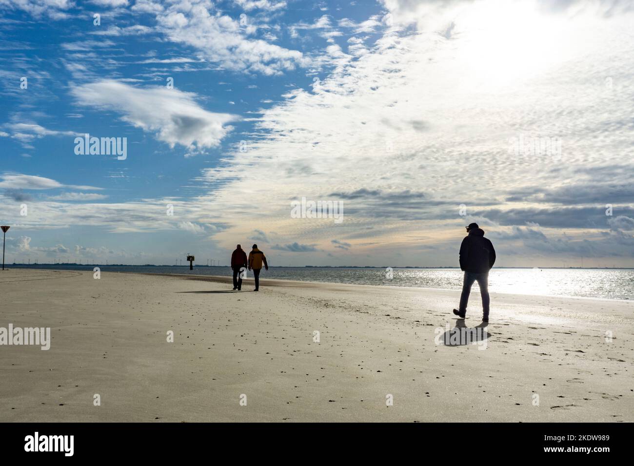 Mare del Nord, Isola di Spiekeroog, autunno, vento forte guida la sabbia sopra le pianure mudali con la bassa marea, camminatore spiaggia, costa occidentale dell'Isola Frisone Orientale, Lowe Foto Stock