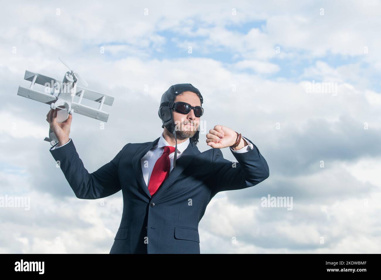 uomo d'affari in tuta e cappello pilota aereo giocattolo di lancio. tempo di controllo Foto Stock