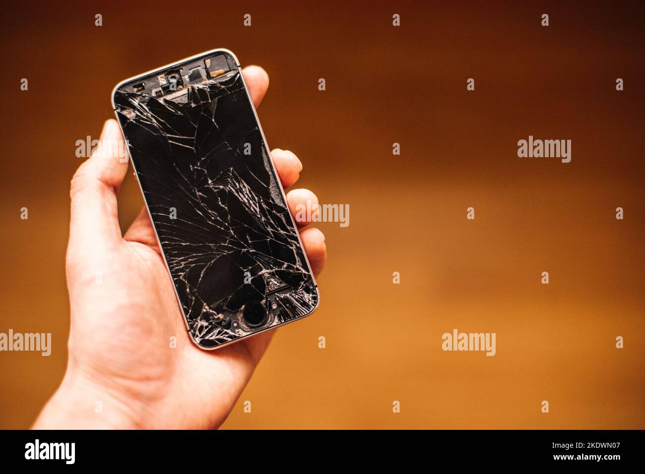 Persona che tiene in mano smartphone rotto con schermo incrinato Foto Stock