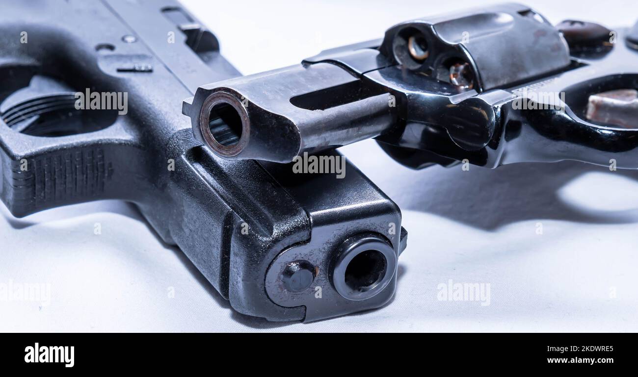 Due pistole, una pistola nera da 9mm mm e un revolver nero con naso a punta di serpente del calibro di 38 mm impilati su uno sfondo bianco Foto Stock
