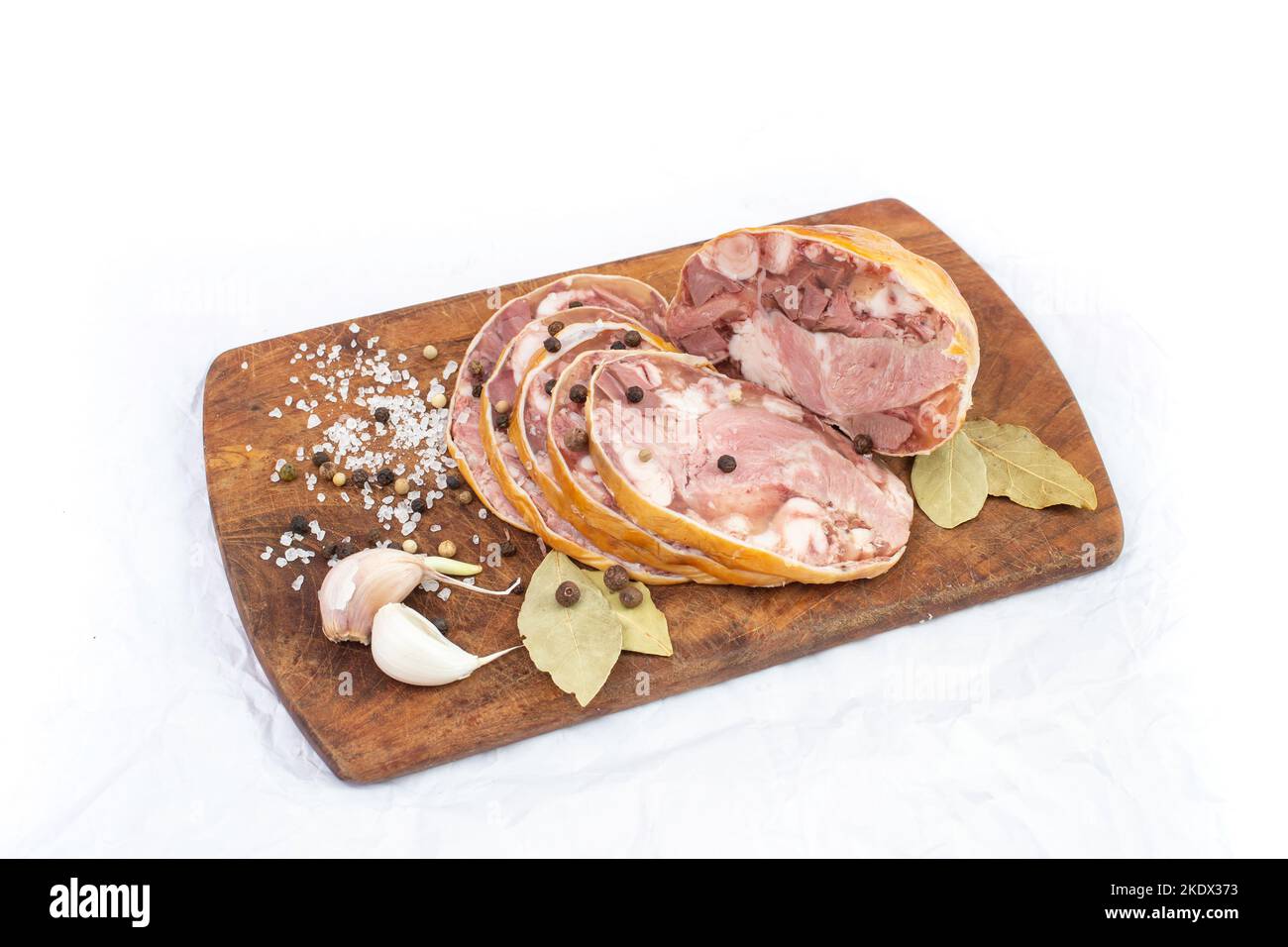 Piatto tradizionale rumeno, toba o piftie, in mammifero naturale, fette su un asse di legno con aglio, foglie di alloro e pepe. Primo piano con messa a fuoco morbida Foto Stock