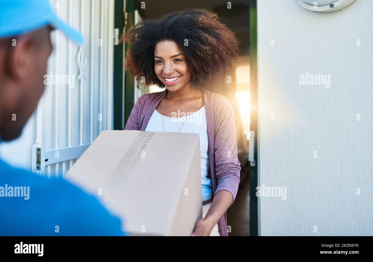 Il vostro pacchetto, maam. Un assistente postale che consegna un pacchetto ad una giovane cliente femminile. Foto Stock