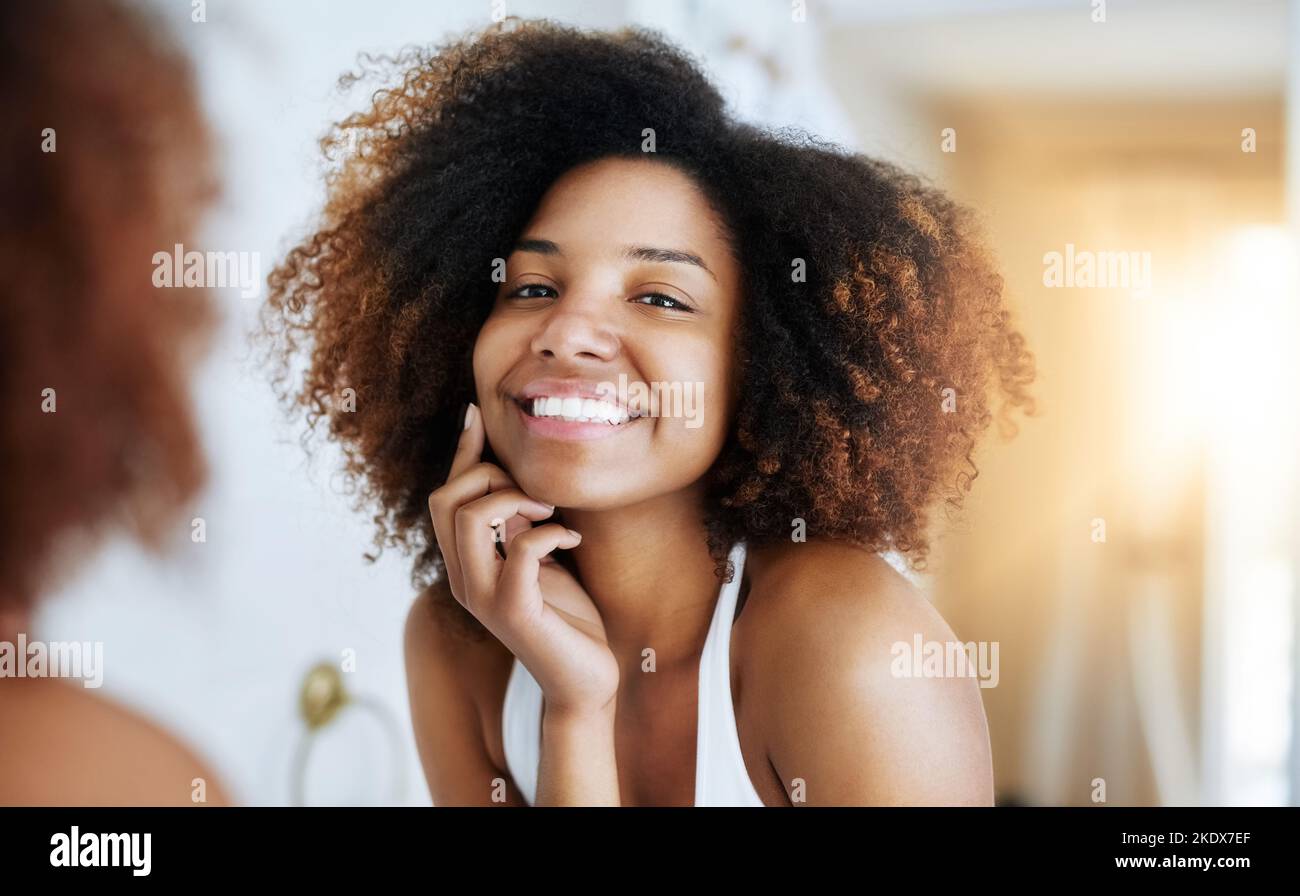 La sua pelle si illumina e si vede. Ritratto di una giovane donna attraente ammirando la sua pelle di fronte allo specchio del bagno. Foto Stock