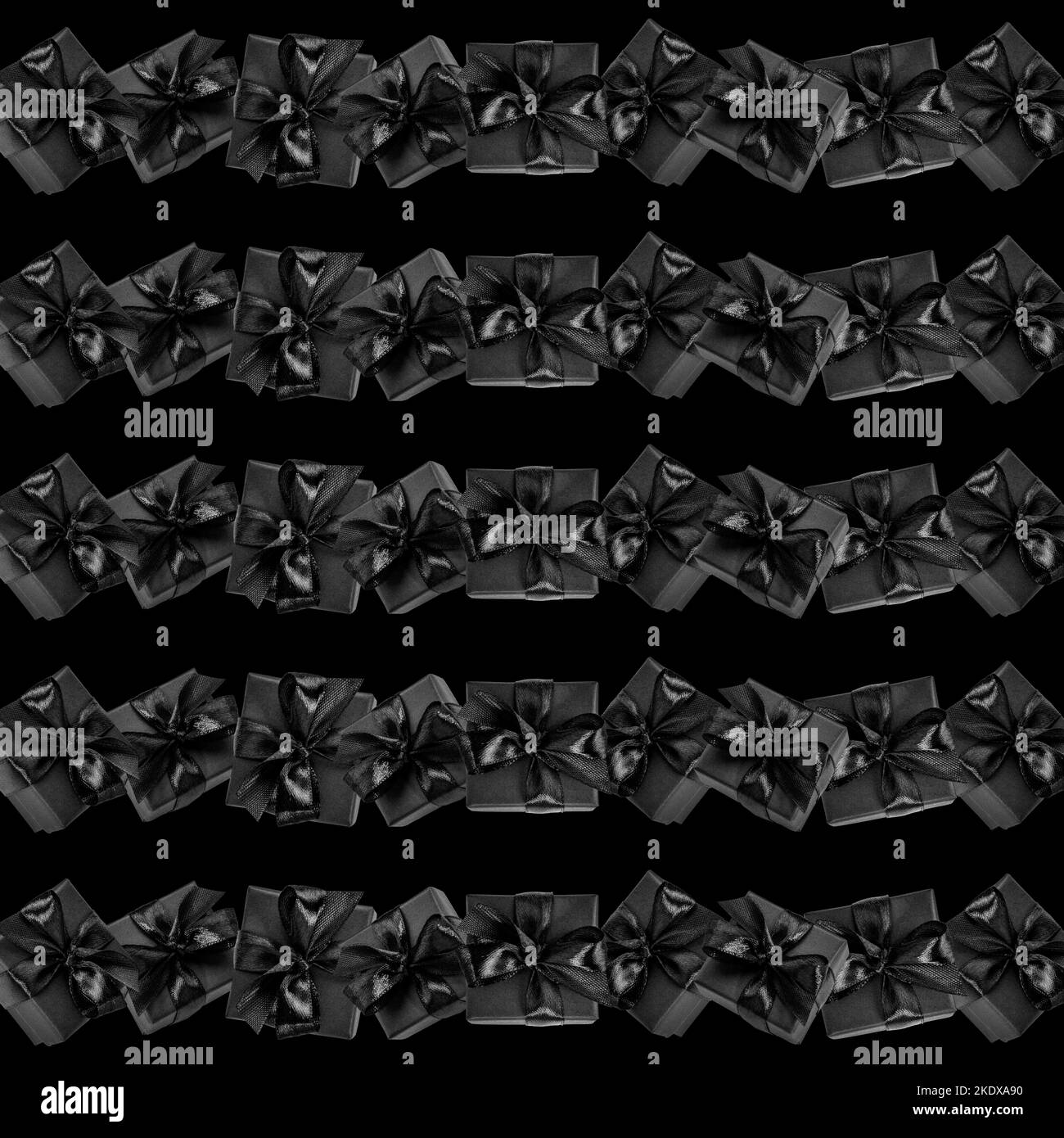 Motivo senza cuciture costituito da file di scatole regalo confezionate in nero con archi su sfondo nero. Immagine pubblicitaria creativa per Black friday, shopping, Boxing Foto Stock