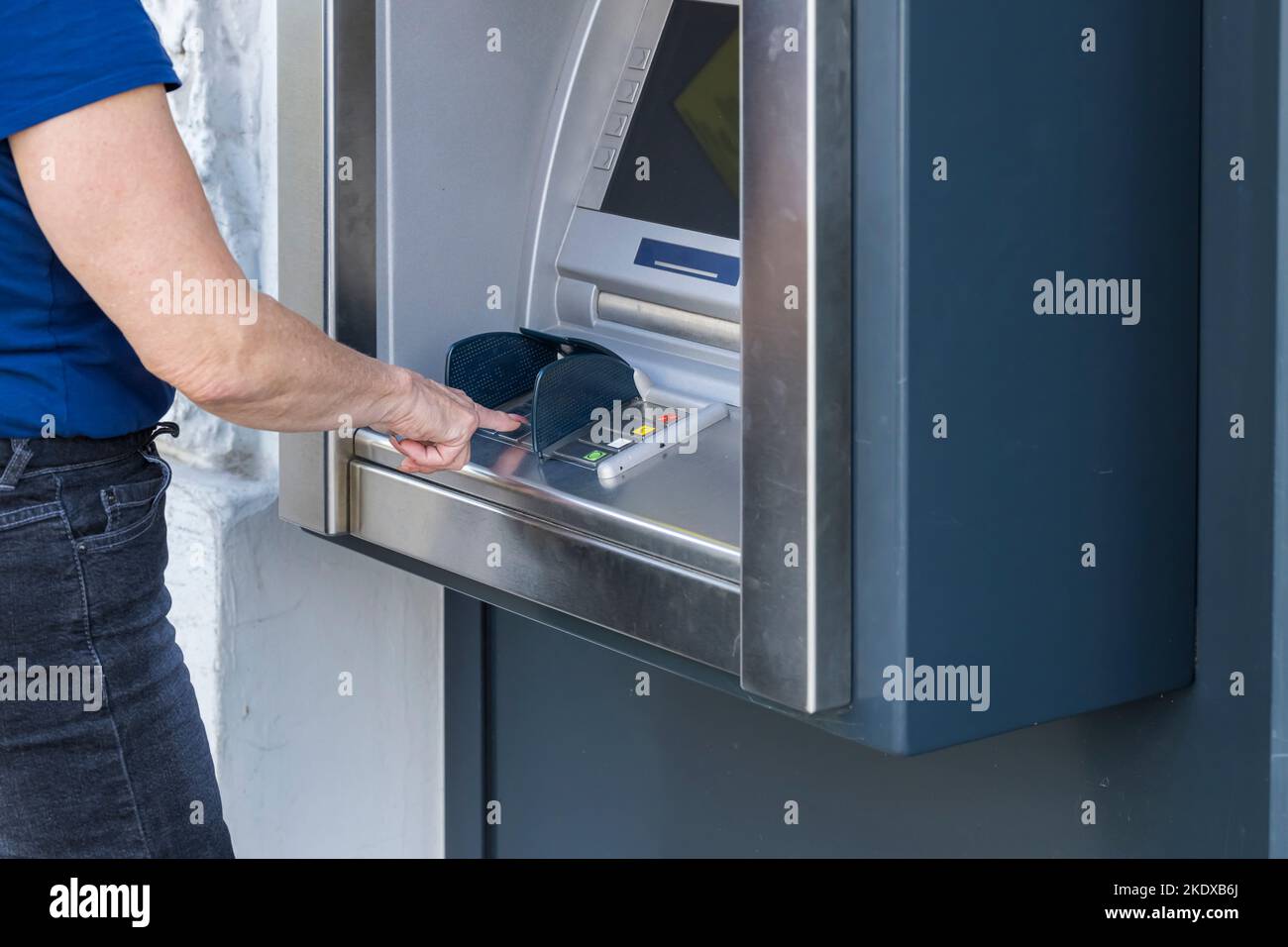Una donna al bancomat digita l'importo Foto Stock