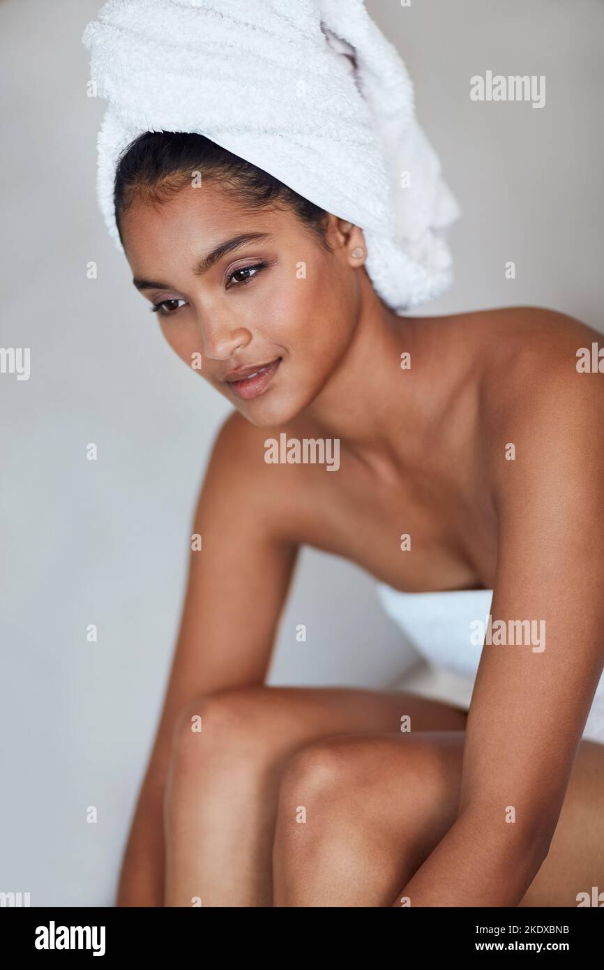 Prendetevi il tempo per essere gentili con la vostra pelle. Una giovane donna attraente e premurosa avvolta in un asciugamano a casa. Foto Stock