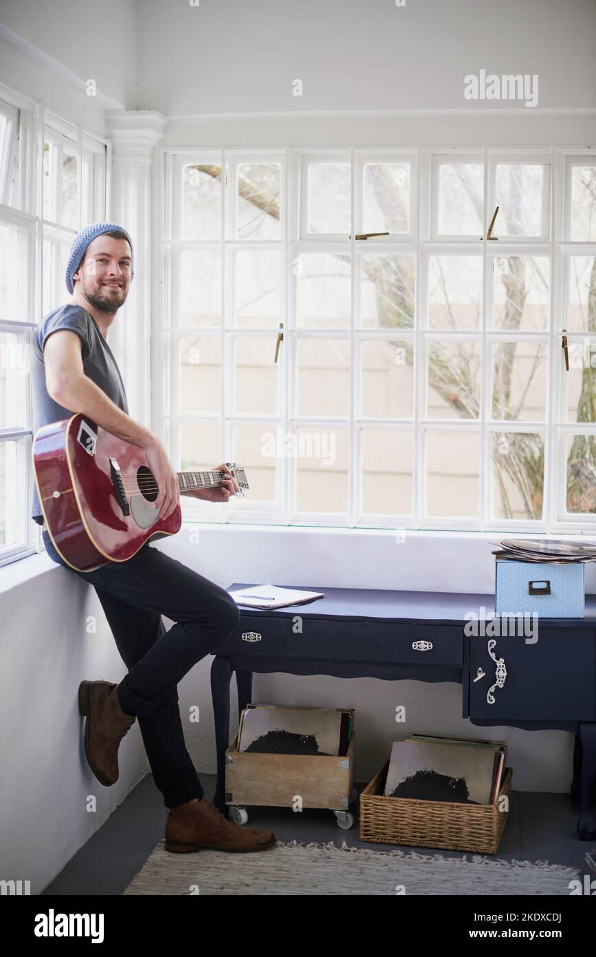 Canzoni così dolce youll sentirsi serenato. Ritratto di un bel giovane che suona una chitarra a casa. Foto Stock