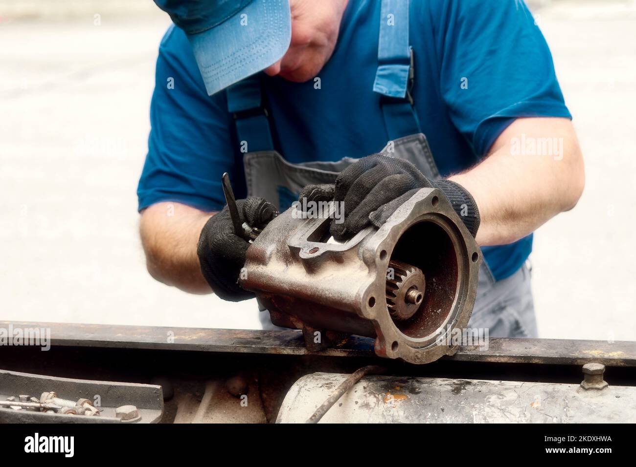 Il meccanico di riparazione dell'automobile ispeziona attentamente la parte. Riparazione meccanica del motore. Flusso di lavoro. Vista frontale. Foto Stock