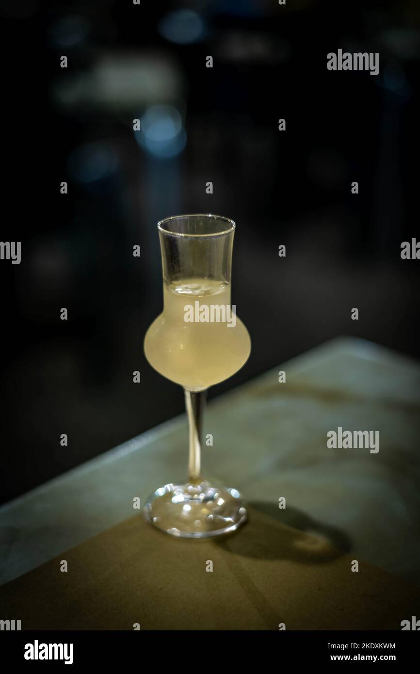 Un bicchiere di limoncello si trova sul tavolo di notte nel patio di un ristorante Foto Stock