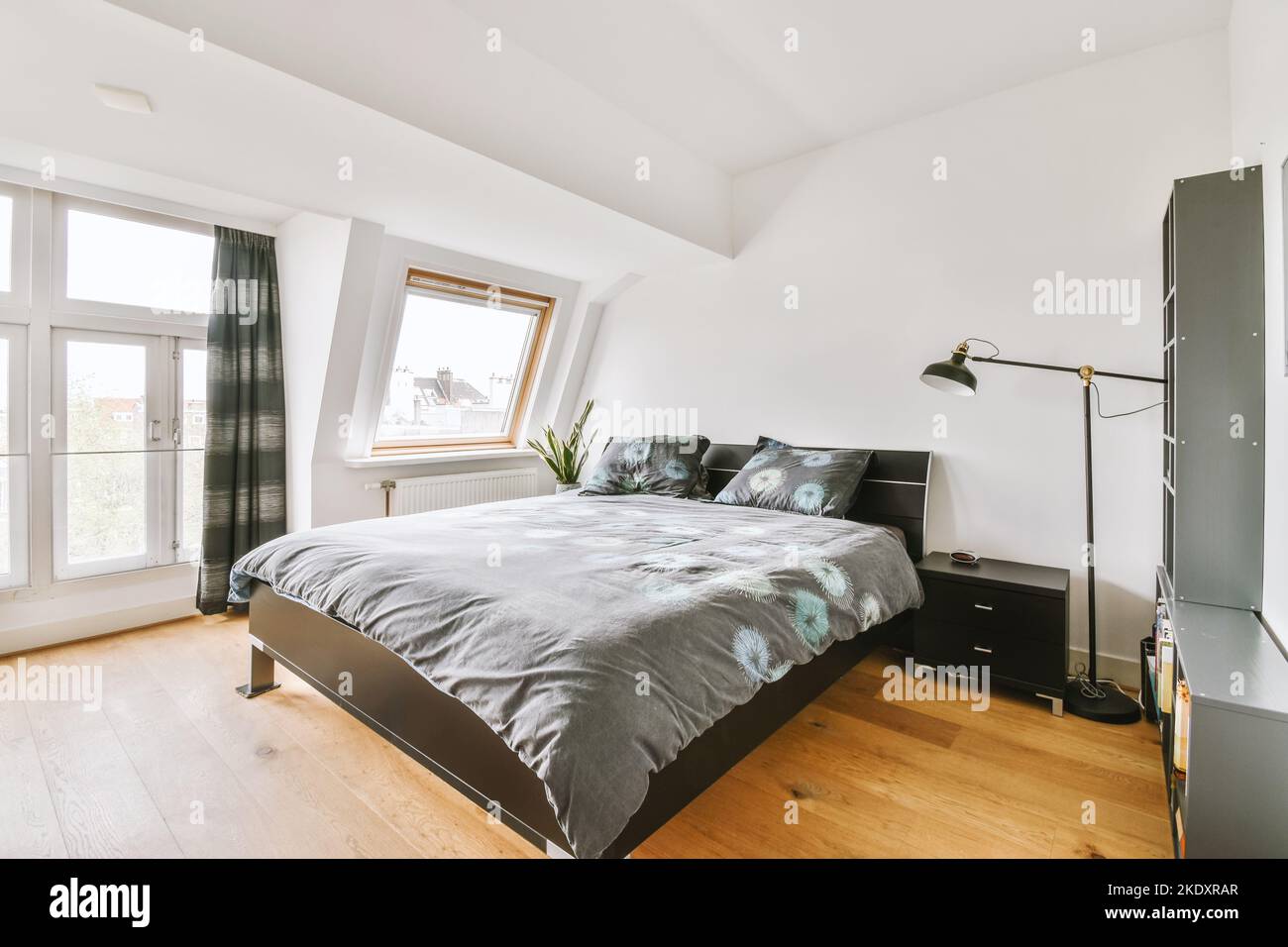 Elegante e semplice interno della camera da letto con parete bianca e letto nero sotto il soffitto bianco con travi Foto Stock