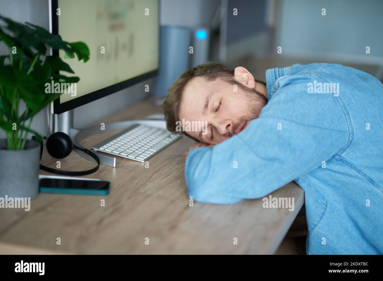 Sviluppatore di software di web designer: caucasico sopportato stanco IT ragazzo dormire e svegliarsi al posto di lavoro in ufficio. Uomo che dorme alla scrivania, stanco di stressante lavoro burnout al lavoro, mancanza di energia Foto Stock