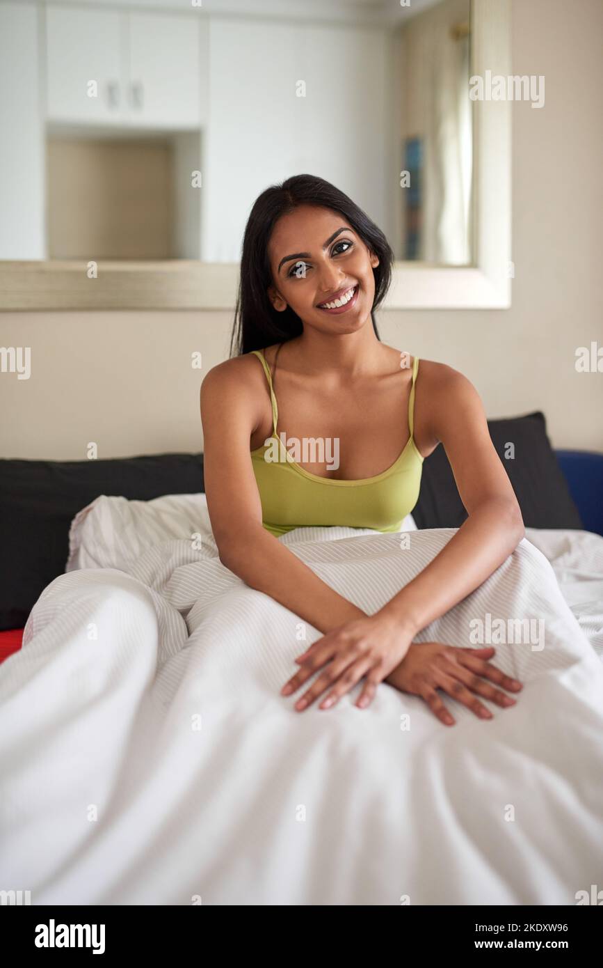 Le mattine rilassanti mi danno motivo di sorridere: Una giovane donna che si sveglia a letto sentendosi ben riposata. Foto Stock