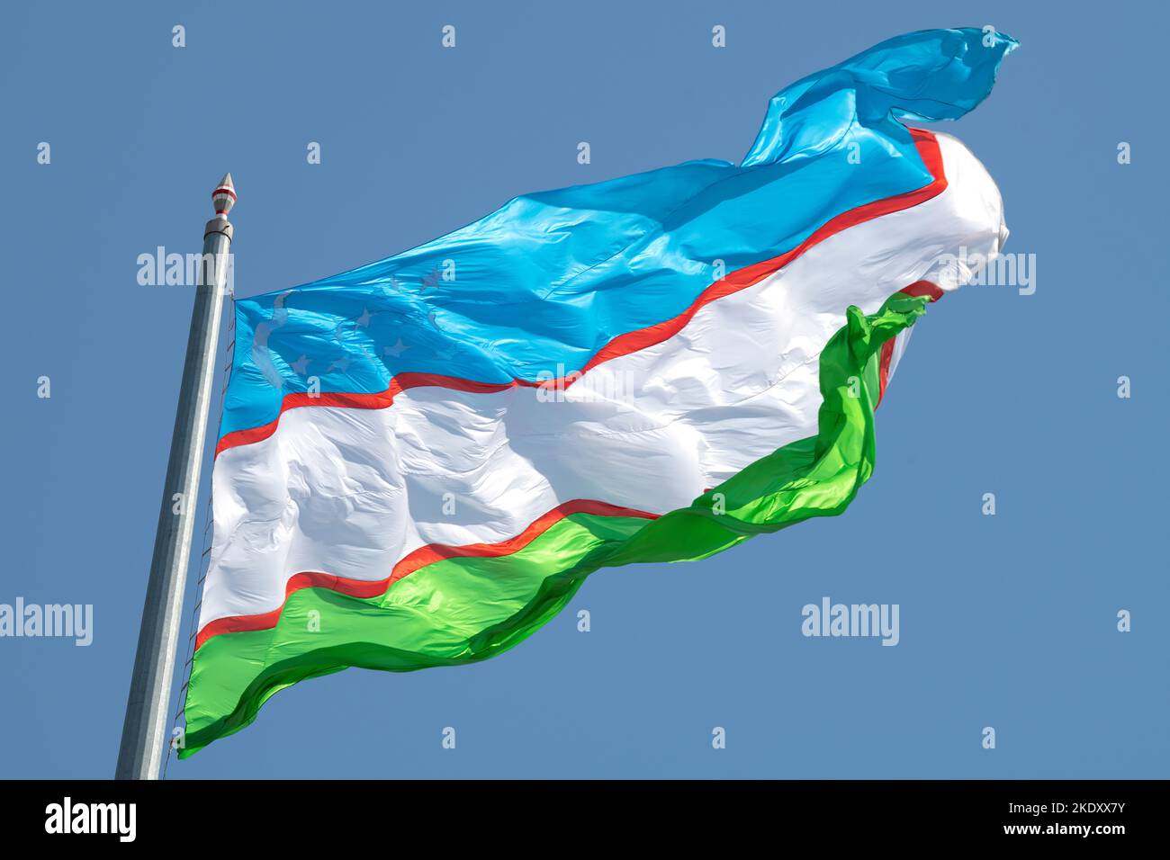 La bandiera uzbeka batte forte vento in una giornata di sole. Uzbekistan Foto Stock