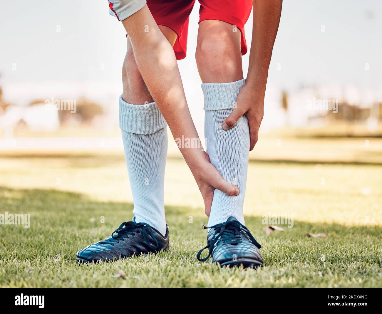 Shin Pain, lesioni e incidenti di un giocatore di calcio che gioca una partita o allenarsi in un campo all'aperto. Fitness, calcio e atleta con feriti, spruchi Foto Stock