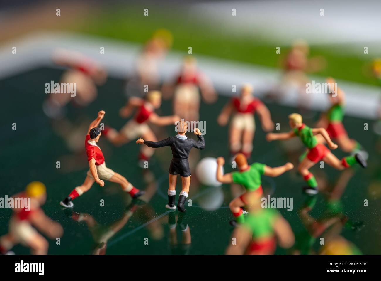 Vista laterale di giocattoli in miniatura figurine calcio (calcio) giocatori su un computer pad (focus sull'arbitro). Foto Stock