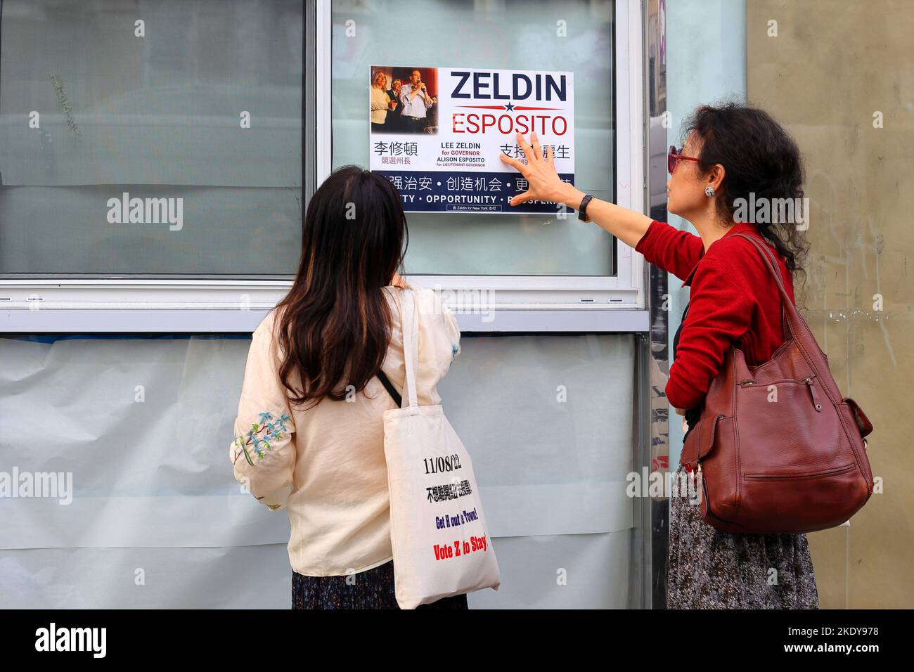 Due operatori della campagna politica dell'Asia-America collocano un poster Zeldin/Esposito su una finestra di un edificio a Manhattan Chinatown, il 6 novembre 2022. Foto Stock