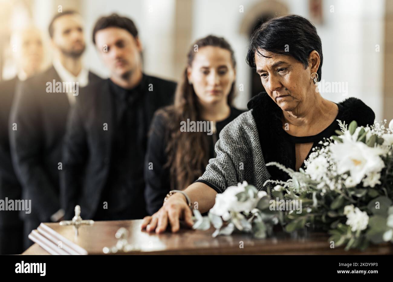 Funerali, morte e bara in chiesa o famiglia cristiana riuniti per sostegno. Religione, gente triste e lutto perdita o religioso cattolico Foto Stock