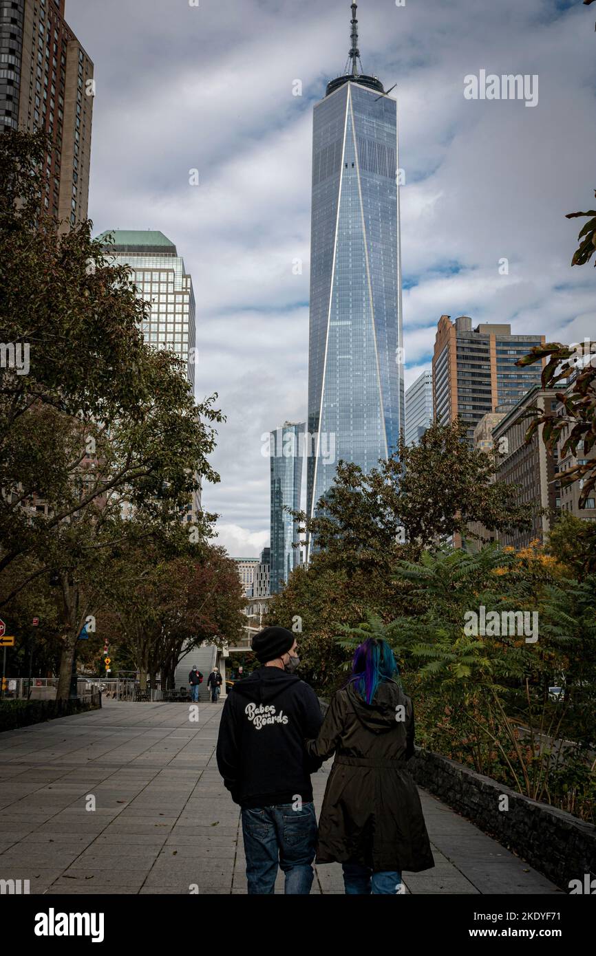 Una vista verticale sul retro di una coppia che cammina lungo un sentiero vicino alla World Trade Center Tower di NYC Foto Stock
