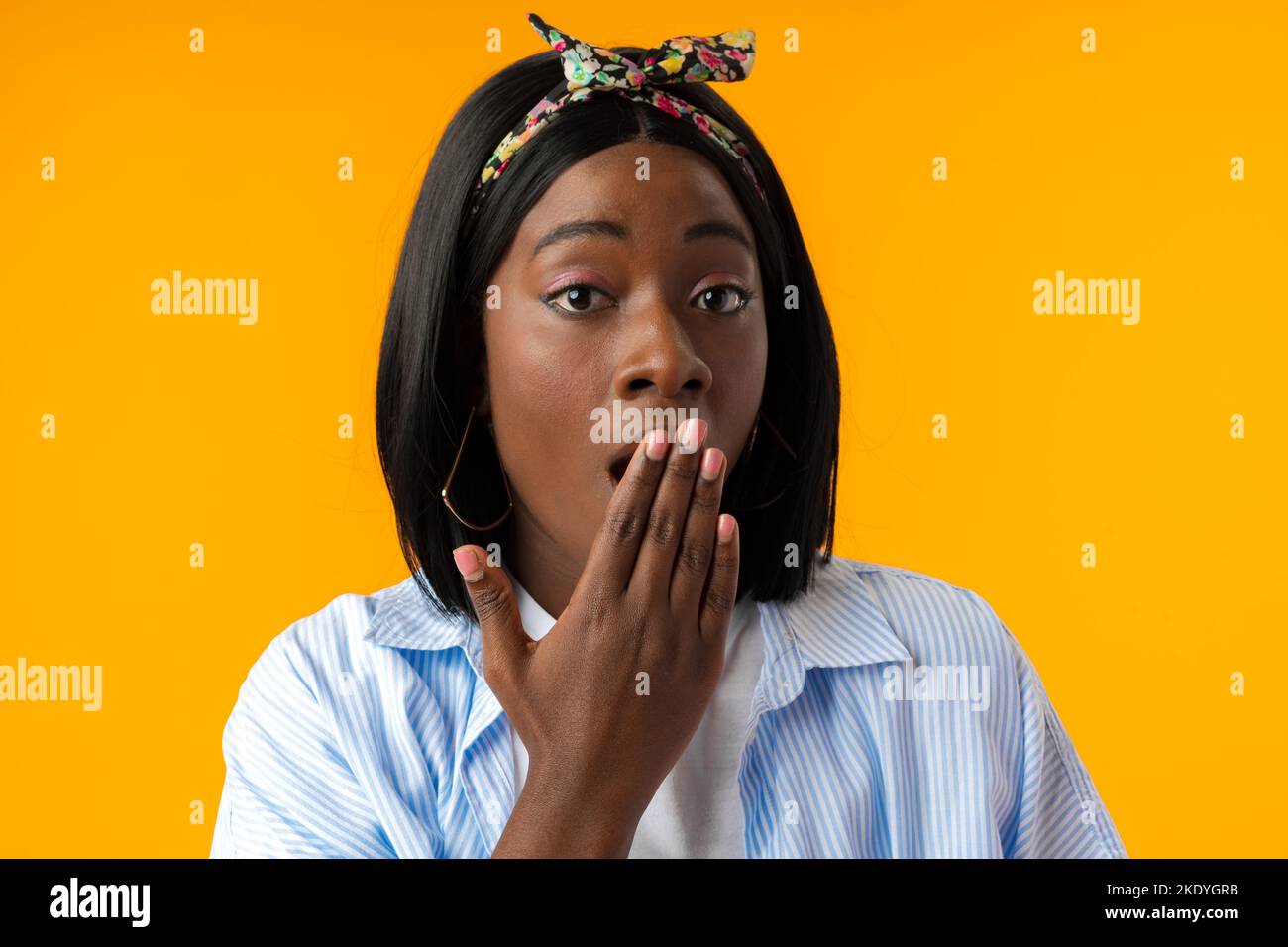 Stordito africano femmina con bocca aperta realizza cattive notizie su sfondo giallo Foto Stock
