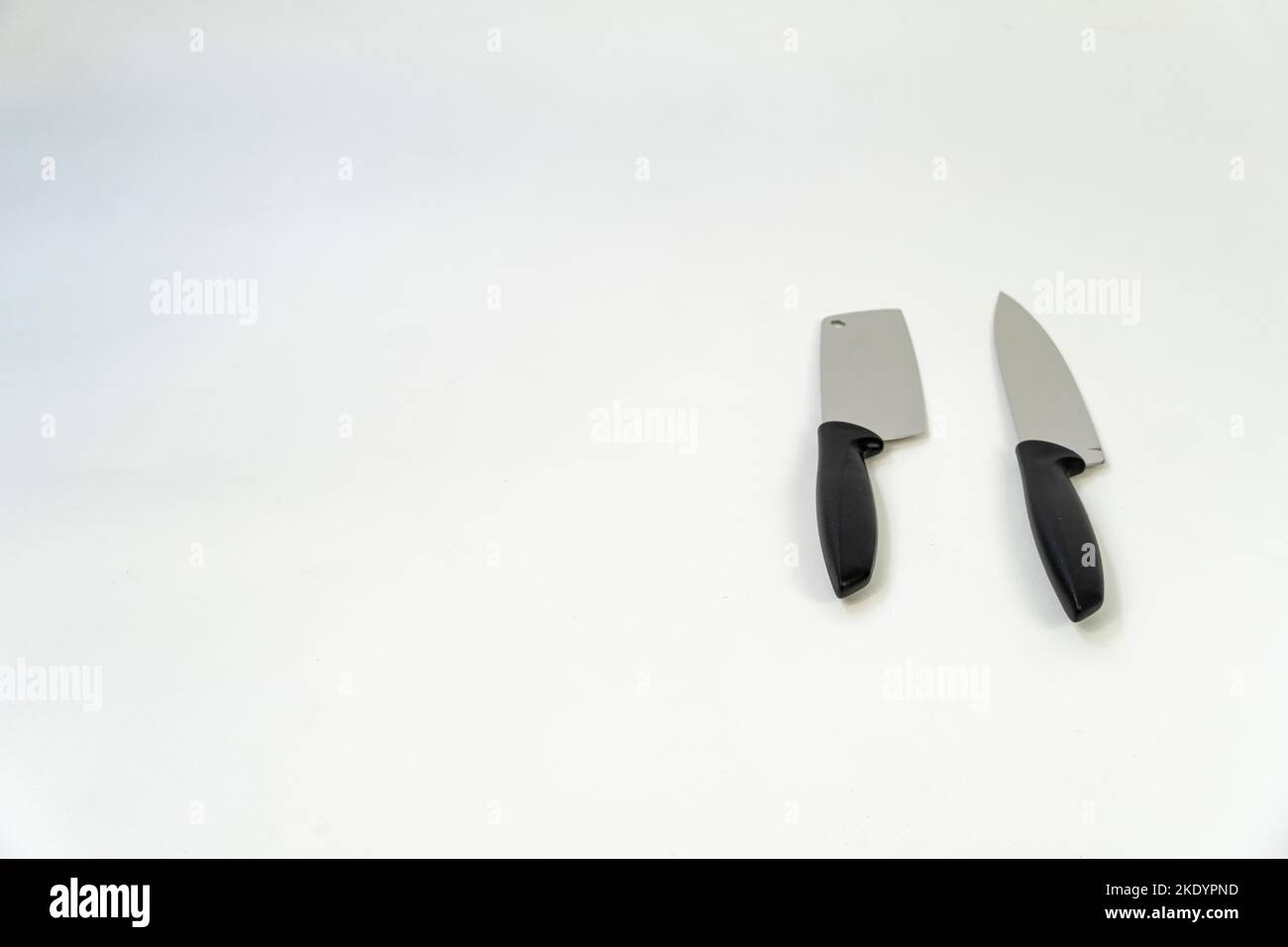 Due coltelli in metallo nero, acciaio affilato con manici in plastica su sfondo bianco Foto Stock