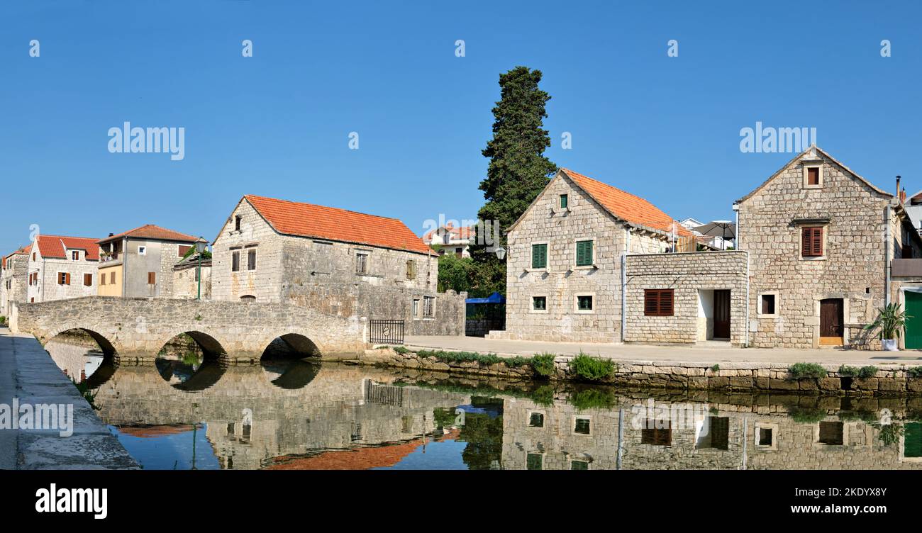 Ponte di pietra e vecchie case storiche nel villaggio di Vrboska, isola di Hvar, Dalmazia, Croazia, Europa. Immagine banner panoramica. Vecchio villaggio di pescatori Foto Stock