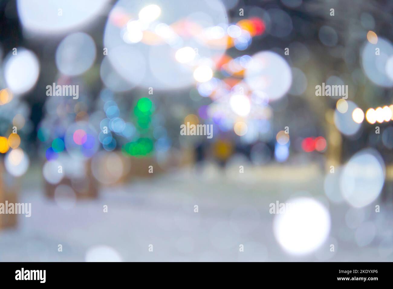 Sfondo sfocato. Strada cittadina durante le nevicate nella notte d'inverno. Molti alberi di Natale decorati, illuminazione, decorazione sulla strada. Festa di Natale di Capodanno. Lanterne ghirlande sugli alberi Foto Stock