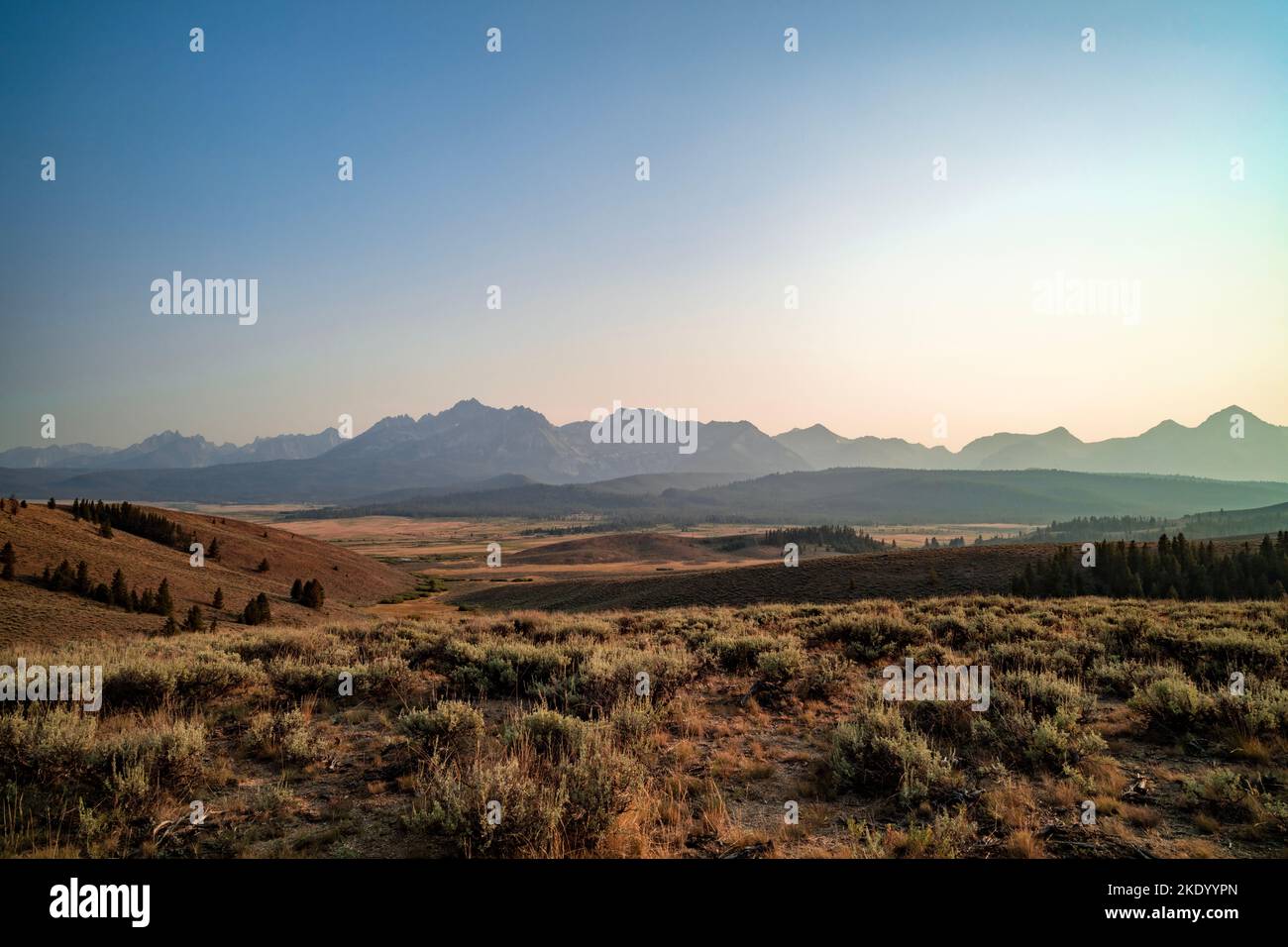 La catena montuosa Sawtooth vista dalle colline a nord di Stanley, Idaho in una serata estiva. Il cielo è fosso a causa del fumo di fuoco della foresta. Foto Stock