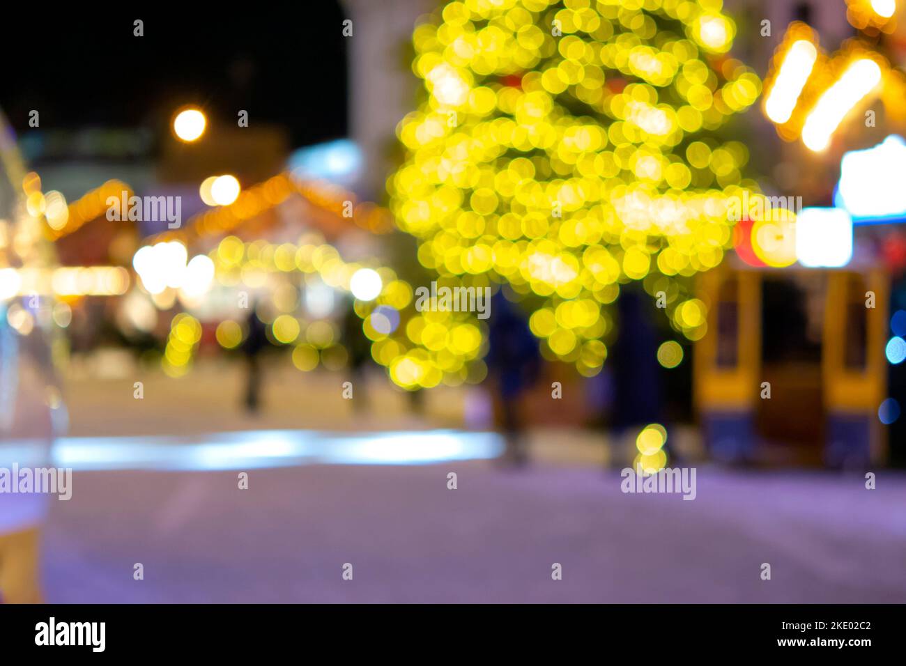 Sfondo sfocato. Albero di Natale, luci decorate, edificio, sagome sfocate di persone che camminano piazza della città durante la notte d'inverno. Bello Capodanno e Natale vacanza sfondo sfocato Foto Stock