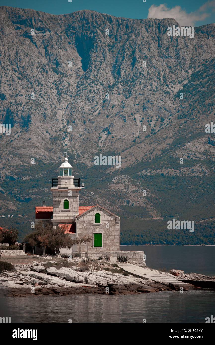 Uno scatto verticale di un bellissimo faro su una piccola terra circondata da un lago in montagna Foto Stock