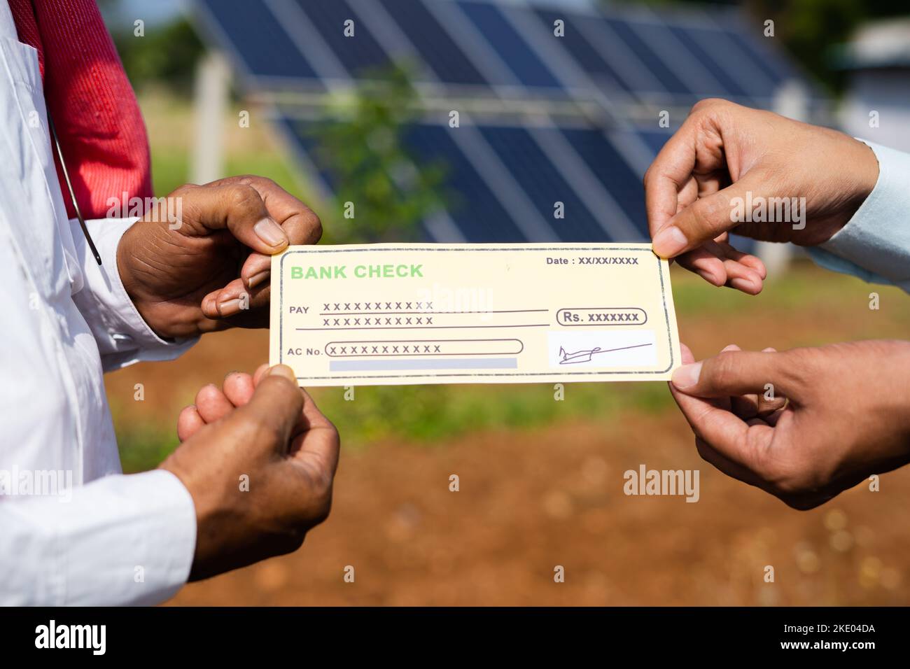 focus on hand, primo piano di agricoltori che ricevono assegni dal banchiere di fronte al pannello solare - concetto di sostegno finanziario per le energie rinnovabili Foto Stock