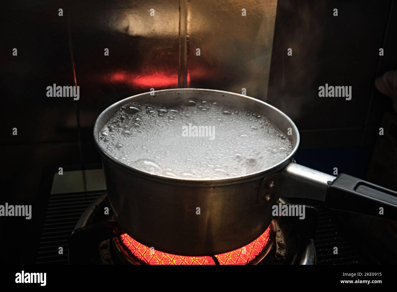 L'acqua sta bollendo e fumo emesso dal calderone d'uovo della pentola sulla stufa. Foto Stock